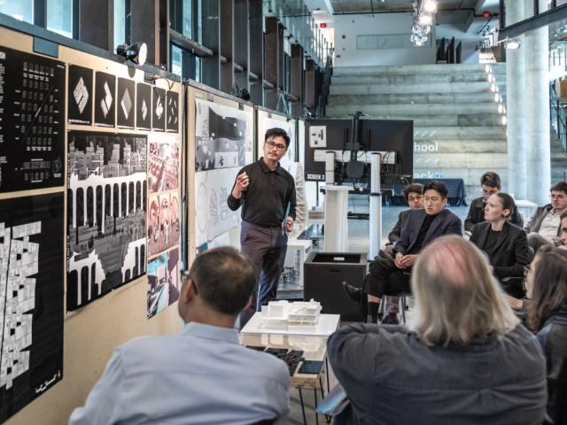 A student presents their work during a review in Knowlton Hall's Center Space