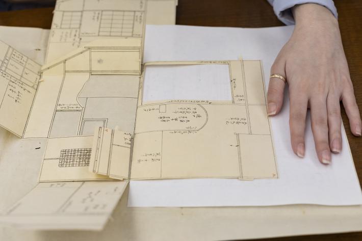 Student unfolds the tea house panels with Japanese text prior to its documentation